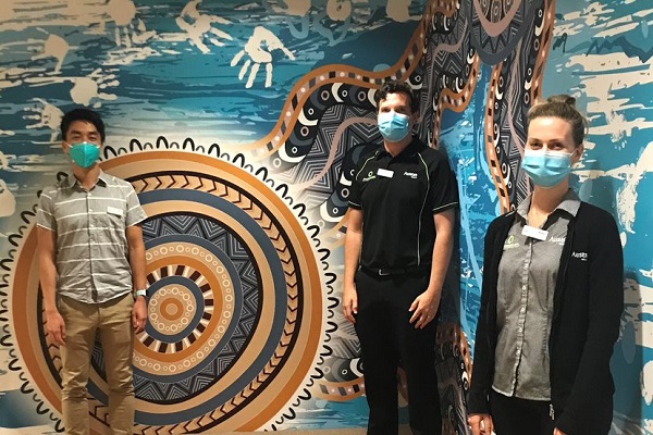 Three Austin Health staff members stand next to Gary Saunders' artwork in the ONJ oncology rooms